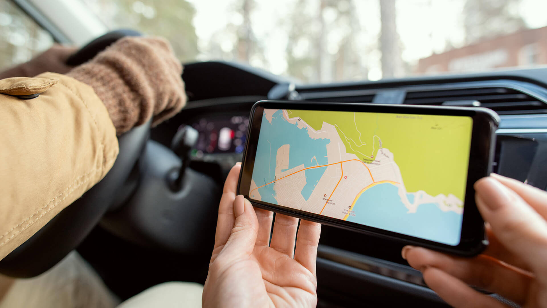 13 najlepszych aplikacji na Androida, ranking, czyli kobieta trzymająca telefon komórkowy z mapą i pokazująca kierowcy gdzie jechać